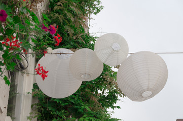 four white Chinese lantern, lampion, hanging on rope in wind