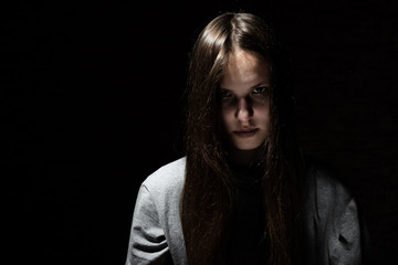 portrait of young teenager brunette girl with long hair in the Gothic style on a black background...