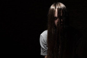 portrait of young teenager brunette girl with long hair in the Gothic style on a black background with copy space