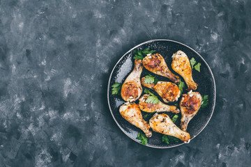Roasted chicken legs with parsley on a dish  dark background top view