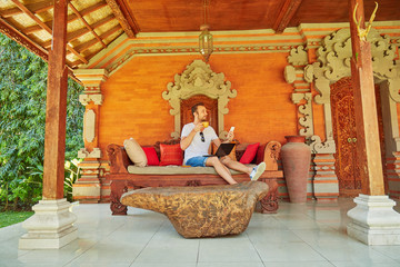 Man with coffee / tea and laptop on a home porch.