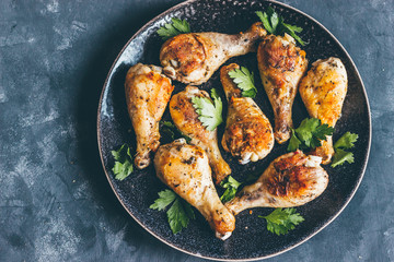 Roasted chicken legs with parsley on a dish  dark style top view