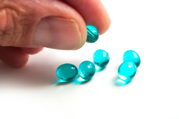 closeup of blue pills in hand on white background