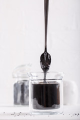 Black tahini sauce in glass jar on white background. Natural paste made from black sesame seeds.
