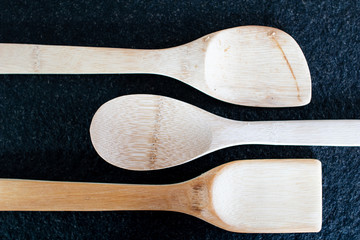 Three wooden kitchen spoons on a black marble table. Useful utensils for cooking, cooking equipment...
