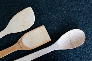 Three wooden kitchen spoons on a black marble table. Useful utensils for cooking, cooking equipment...