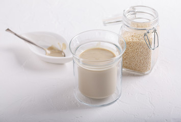 Tahini sauce in glass jar on white background. Natural paste made from sesame seeds.