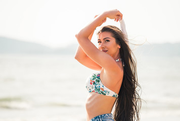 Naklejka premium Young attractive and beautiful happy Caucasian woman posing smiling with white scarf blowing the wind in tropical summer beach