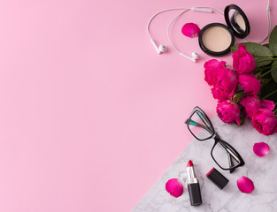 Obraz na płótnie Canvas Cosmetics, makeup brushes, lipstick, powder and glasses with flowers on trendy pink marble background top view