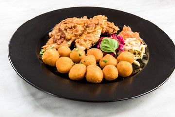 Fried chicken with potato balls and salad, restaurant serving portion