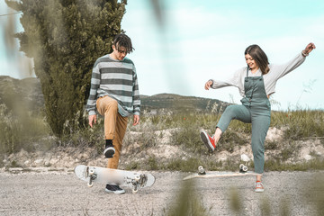 Young couple riding a skateboard on a road. Concept of millennials Skateboarders