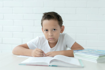 The boy teaches lessons , prepares for school writes and reads textbooks on a white background