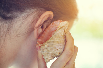 young happy woman listening to seashell