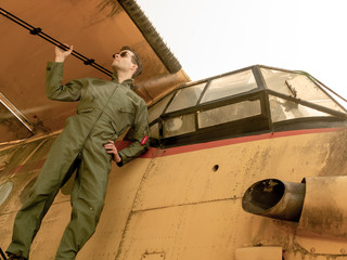 A handsome young pilot standing on the wing of a plane