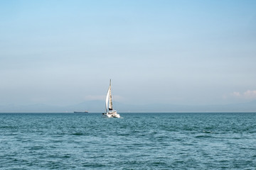 Obraz premium Luxury yacht with white sails in open sea at beautiful sunny day. Small waves on the sea and white clouds on horizon line. Weekend getaway from city. Wonderful world. Natural background. 