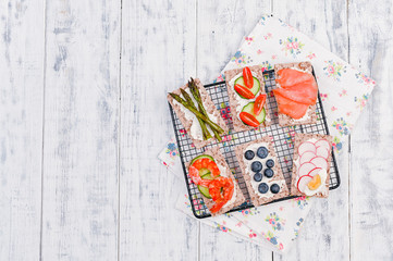 Snack sandwiches with different ingredients and flavor on a white wooden table. Top view. Free space for text.