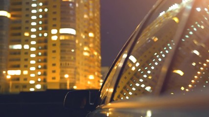 The car rides on a background of buildings. evening night time