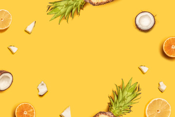 Juicy tropical fruits on a yellow background: oranges, coconuts, lemons, pineapples.
