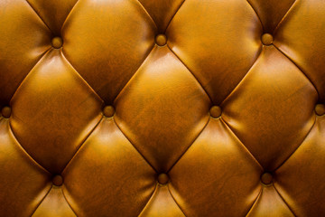 The brown soft leatherette background with asymmetrical buttons. Soft and expensive furniture elements. Luxury background