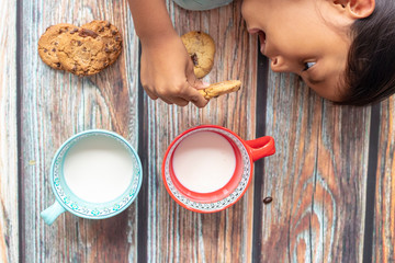 Cute little girl eating cookies with milk