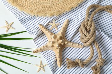 Fototapeta na wymiar Tablecloth, straw hat, starfishes, sea rope and palm leaves on white background, top view and closeup. Summer vacation