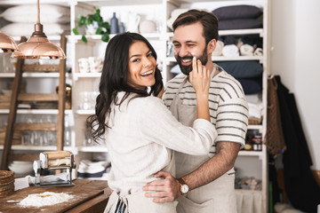 Portrait of young couple hugging together while cooking in kitchen at home