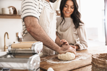 Portrait of caucasian couple mixing the dough while cooking together in kitchen at home