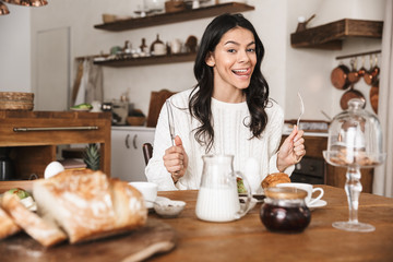 Obraz na płótnie Canvas Portrait of happy caucasian woman 30s having breakfast in kitchen at home