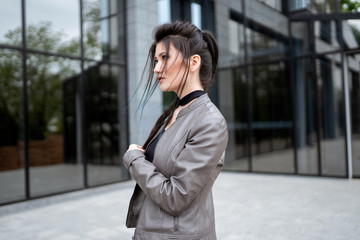 Obraz premium Street style photosession. Beautiful asian girl standing near modern house. Not looking in camera.