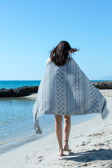 Pretty young girl wrapped in beach towel poses to camera. Full length photo shoot and wonderful hair. Healthy, beauty and summer holiday concept.