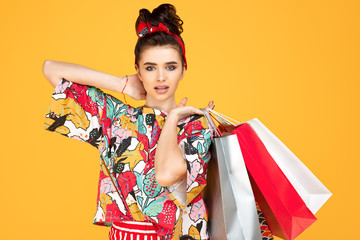 Young happy caucasian woman in casual colorful clothes holding bags and shopping over orange background. Shopping and sales concept.