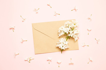 Mockup envelope with branches of lilac on a pink background
