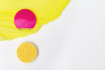 Accessories for cleansing skin, electric cilicone brush red colored and cosmetic sponge from cellulose. Alternative. New and old. Beauty and skincare concept. Flat lay. Top View.