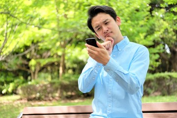 公園でスマホ　携帯を操作する三十代男性