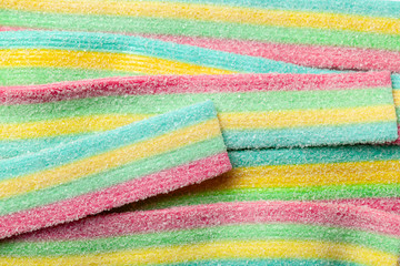 Yellow blue green and red striped jelly sweets sprinkled with sugar.