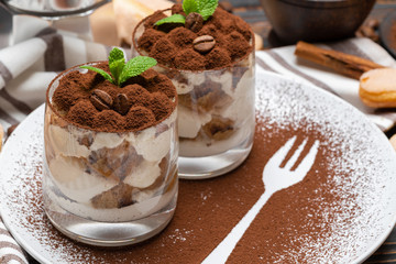 Classic tiramisu dessert in a glass on wooden background