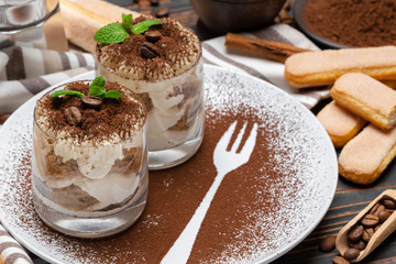 Classic tiramisu dessert in a glass on wooden background