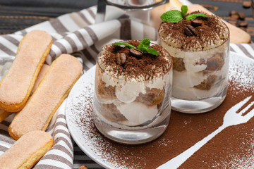 Classic tiramisu dessert in a glass on wooden background