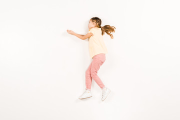 top view of adorable child gesturing while lying on white