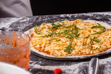 young woman in a gray aprong prepares a vegetarian pizza