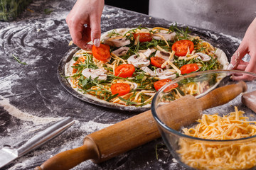 young woman in a gray aprong prepares a vegetarian pizza