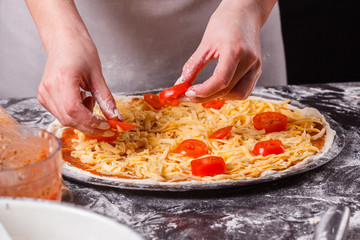 young woman in a gray aprong prepares a vegetarian pizza