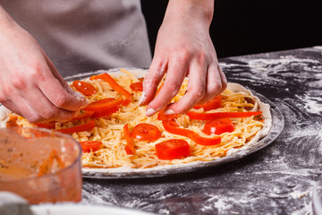 young woman in a gray aprong prepares a vegetarian pizza