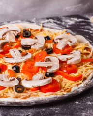 young woman in a gray aprong prepares a vegetarian pizza