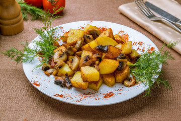 Fried potatoes with mushrooms on white plate