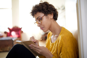 Close up young african american woman with glasses writing in book