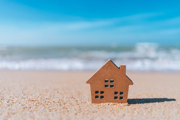 Fototapeta na wymiar Small home model on sand beach with blue sky background.