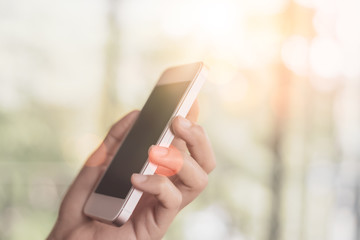 Woman hand using smart phone at outdoor nature park with sunset sky abstract background.