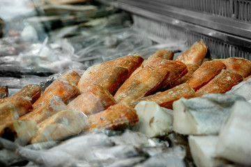 Close up of frozen seafood - red grouper, pollock, in the market of a fish shop, supermarket, horizontal frame, side view