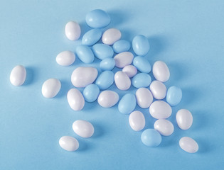 Assorted fullcolor blue and white candy dragees on blue background.